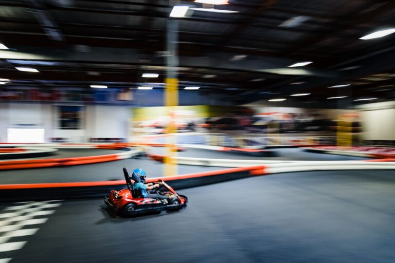 Kind fährt ein rotes Kart auf einer Indoor-Kartbahn