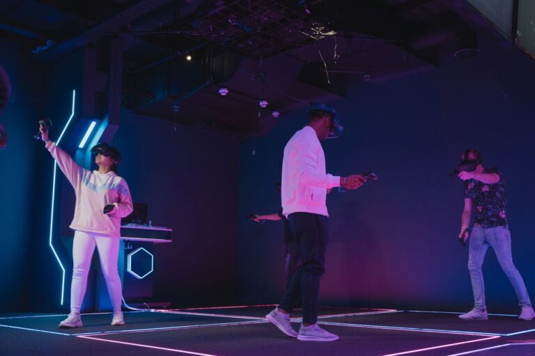 Drei Menschen mit VR-Brillen spielen gemeinsam in einem Raum mit Neonlicht